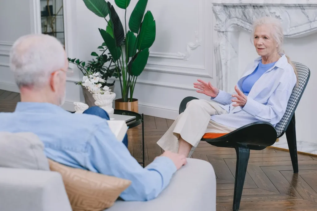 Elderly couple discussing in a stylish living room with plants.