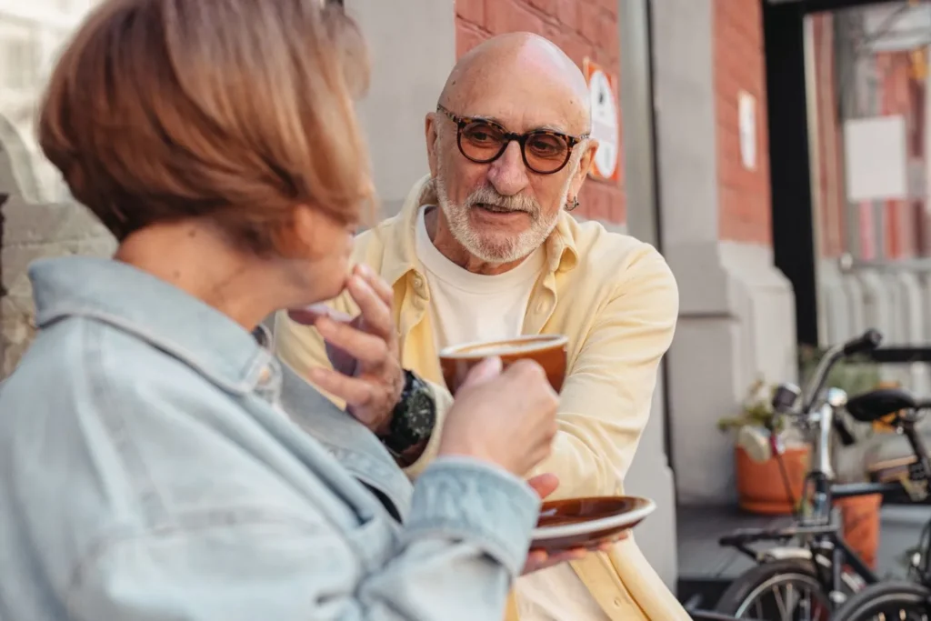 A senior couple sharing a warm moment with coffee outdoors, showcasing love and companionship