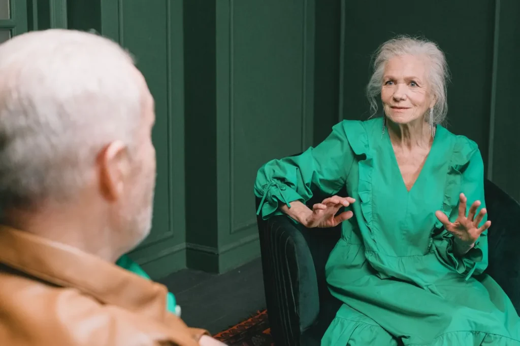 Senior couple seated indoors having an engaging conversation. Warm expressions and gestures highlight their emotions