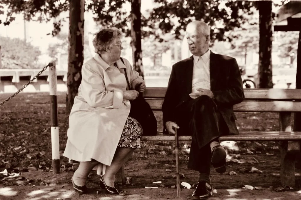 A senior couple enjoys a peaceful conversation on a park bench during the day.
